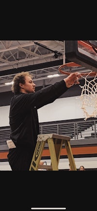 a man standing on a ladder in front of a basketball hoop